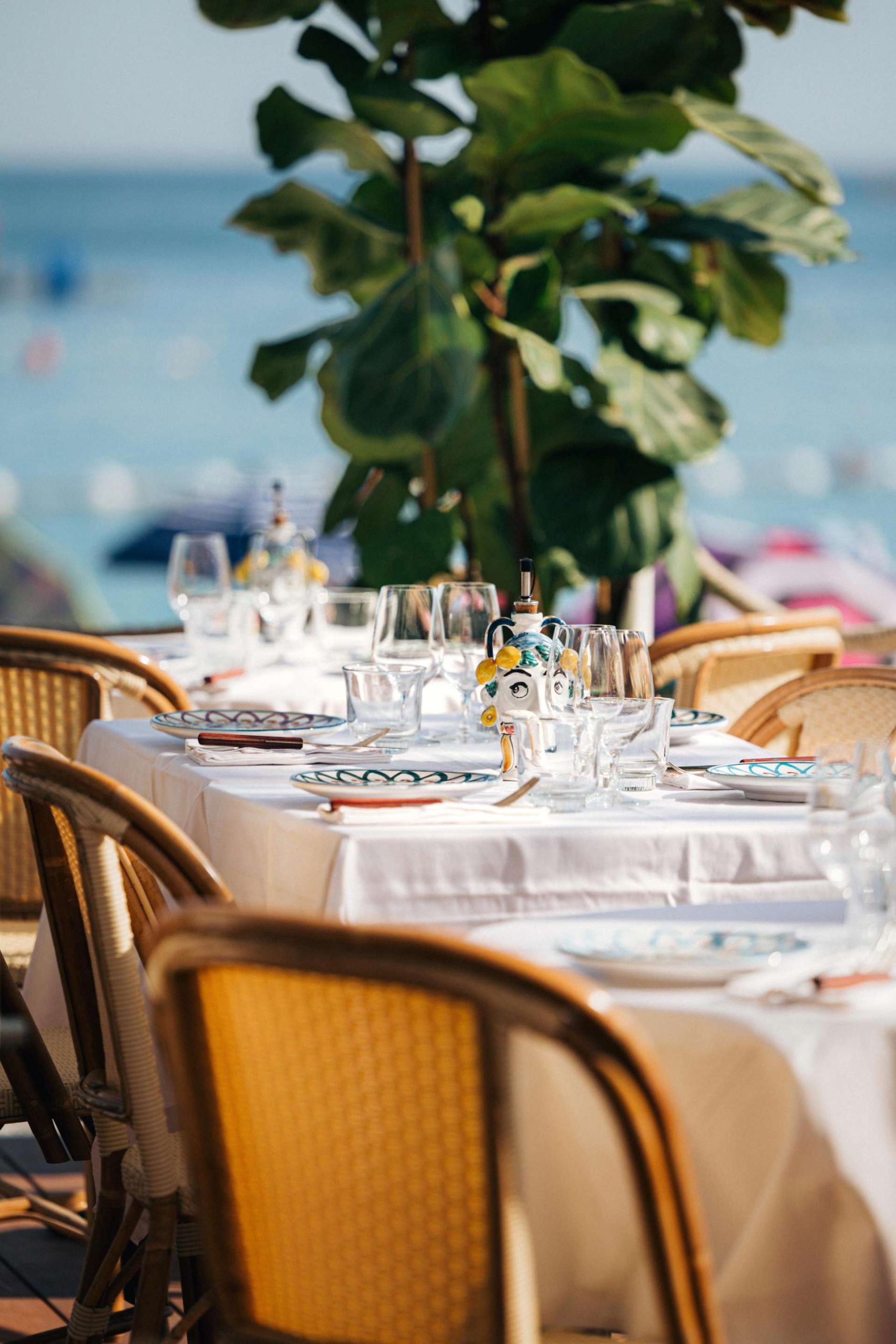 Photo des tables sur la terrasse avec vue sur la mer en arrière plan