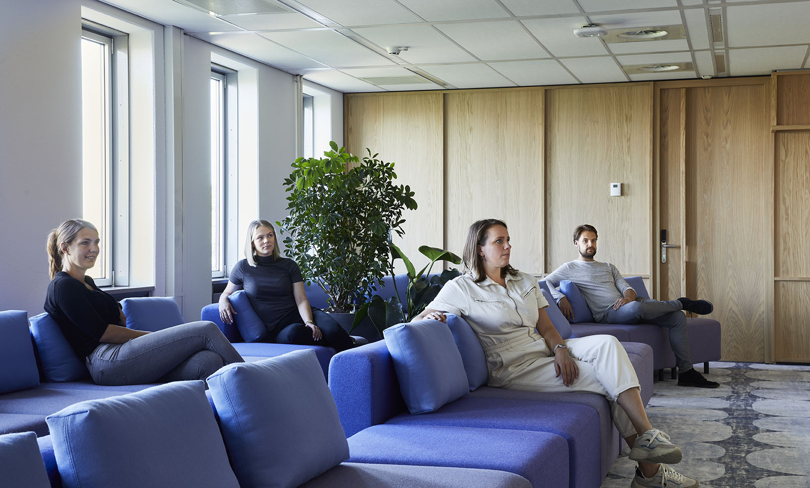 Salle de projection avec des personnes attentives sur des canapés de couleur bleu