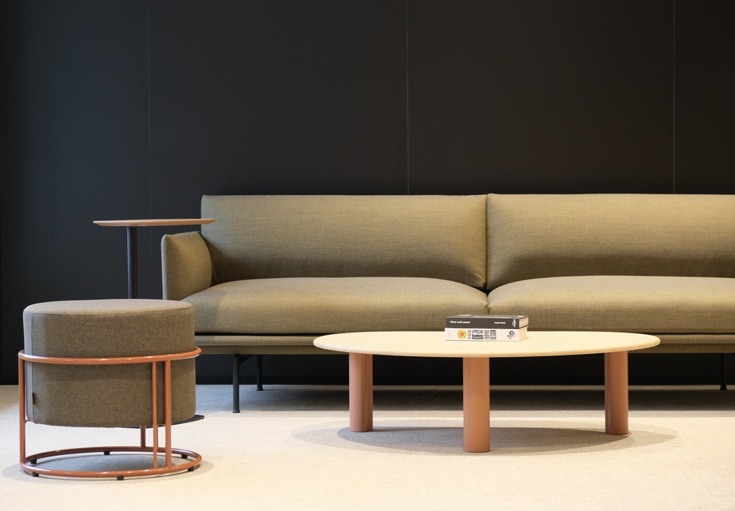 Grand canapé vert olive avec armature en bois, pouf assorti et table basse beige et bois.
