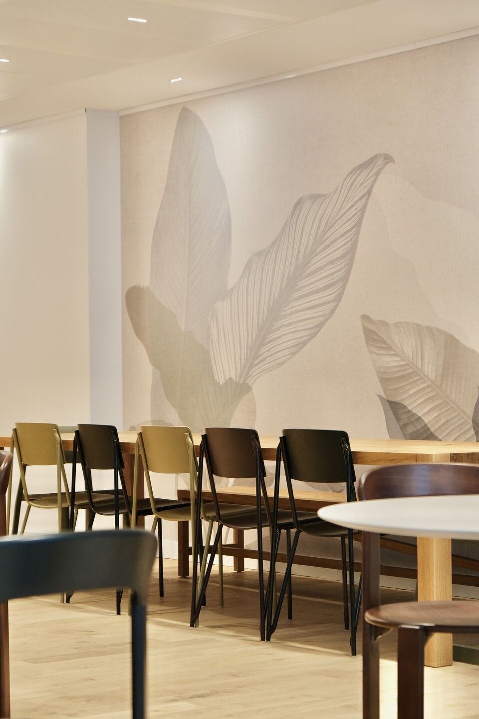 Salle de restauration avec papier peint beige avec de grandes feuilles gris clair légère dessus