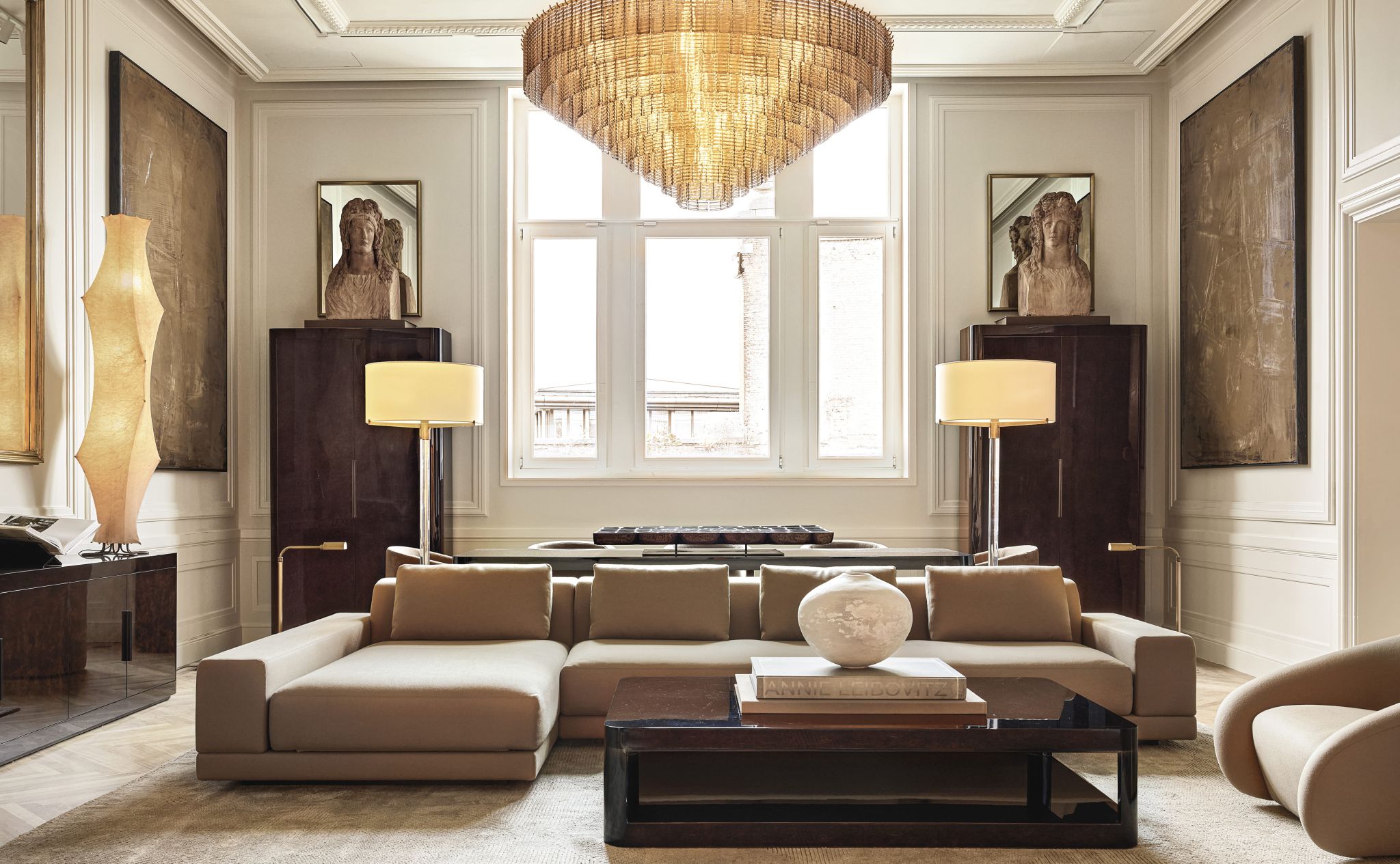 Salon avec grand canapé avec méridienne, table basse carré devant, un grand lustre surplombe l'ensemble - RH