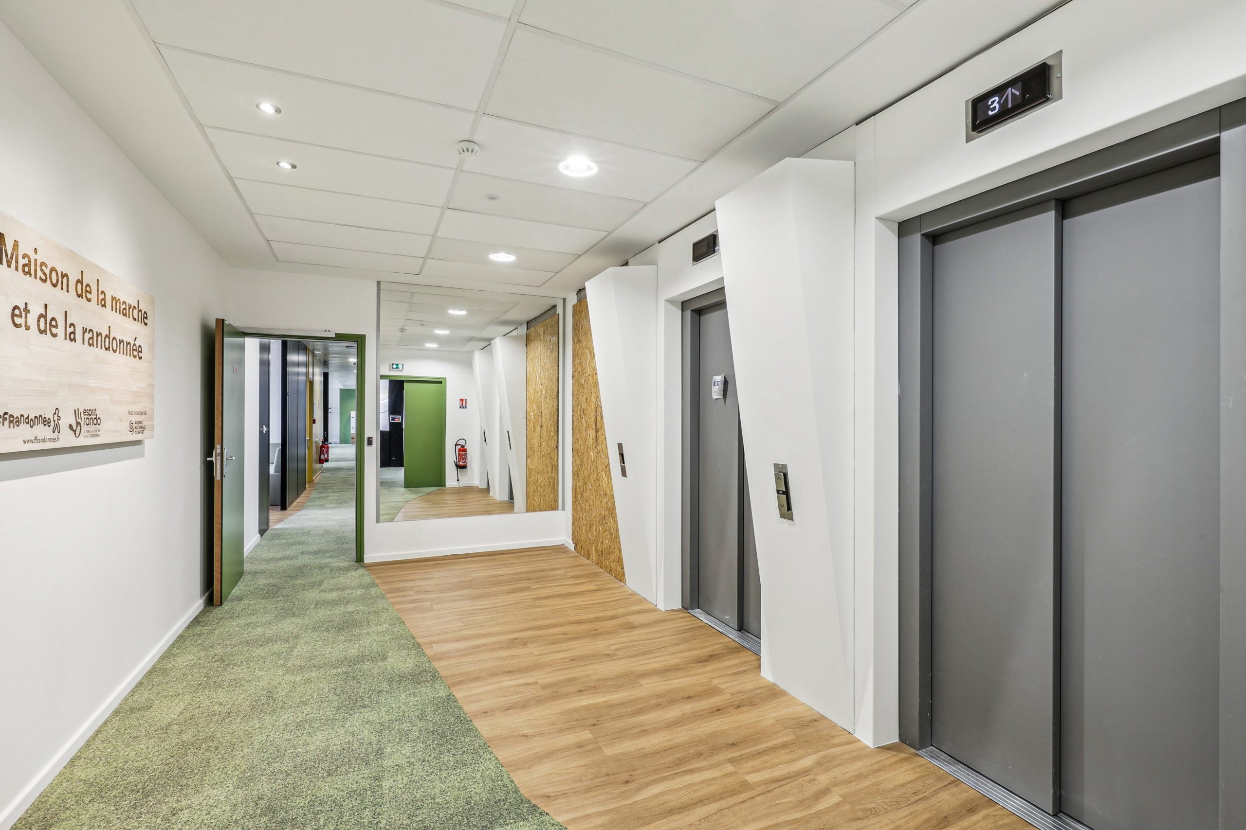 Couloir, porte d'ascenceur, sol en parquet et moquette