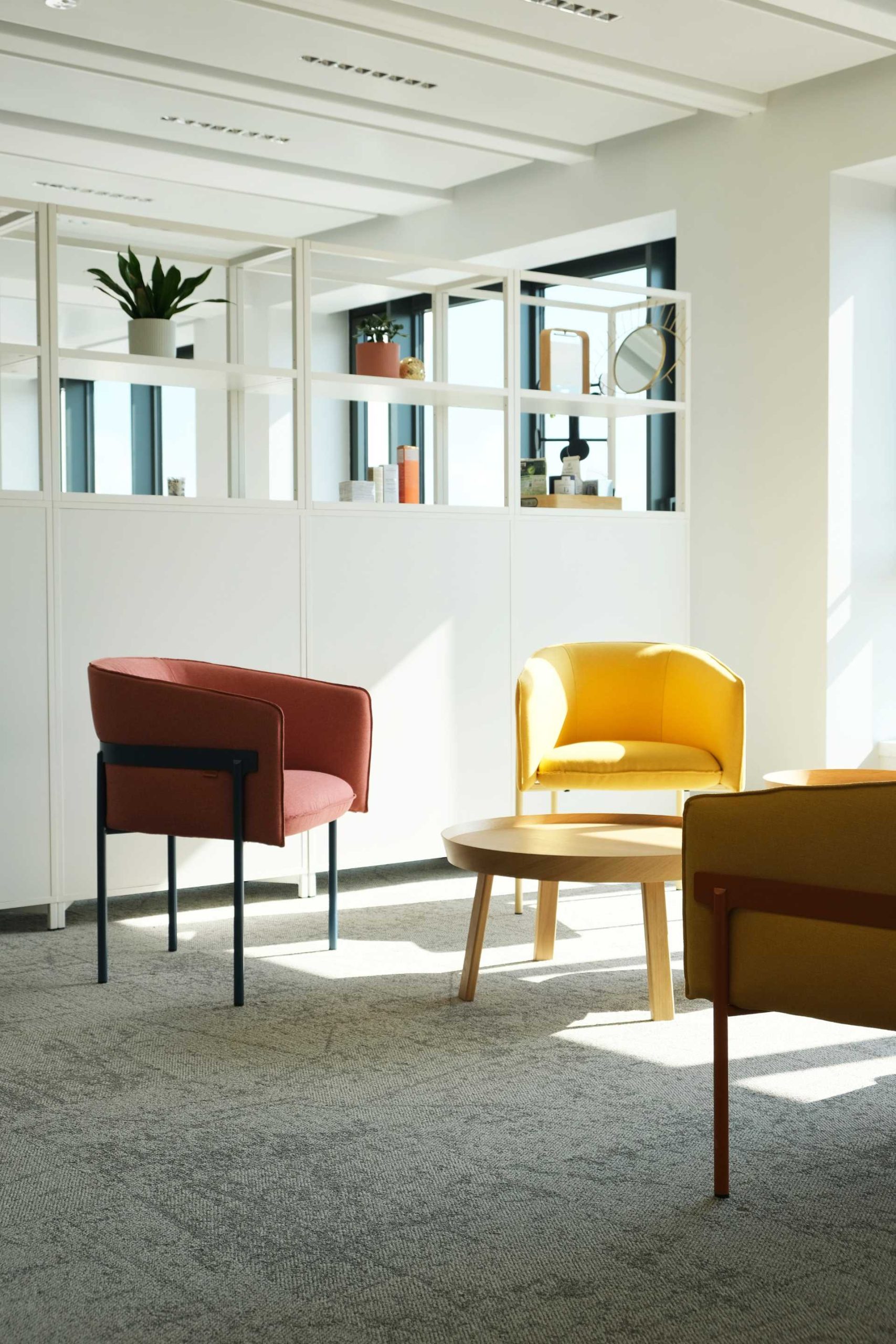 Petit salon avec fauteuils rouge et jaune, table basse en bois clair, chez NAOS, par Parella