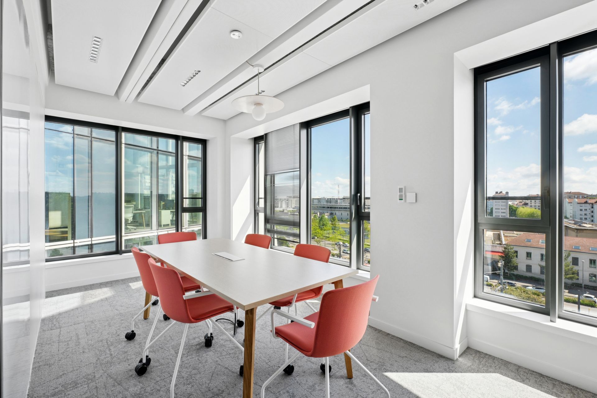 Petite salle de réunion avec table blanche et sièges rouges, chez NAOS, par Parella