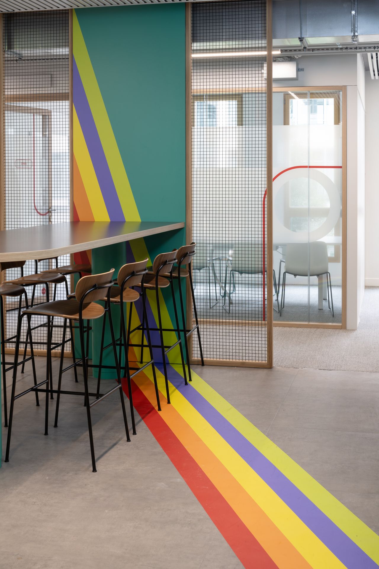 Table et chaise haute, sur le mur des bandes colorées démarrent sur le mur et se poursuivent au sol