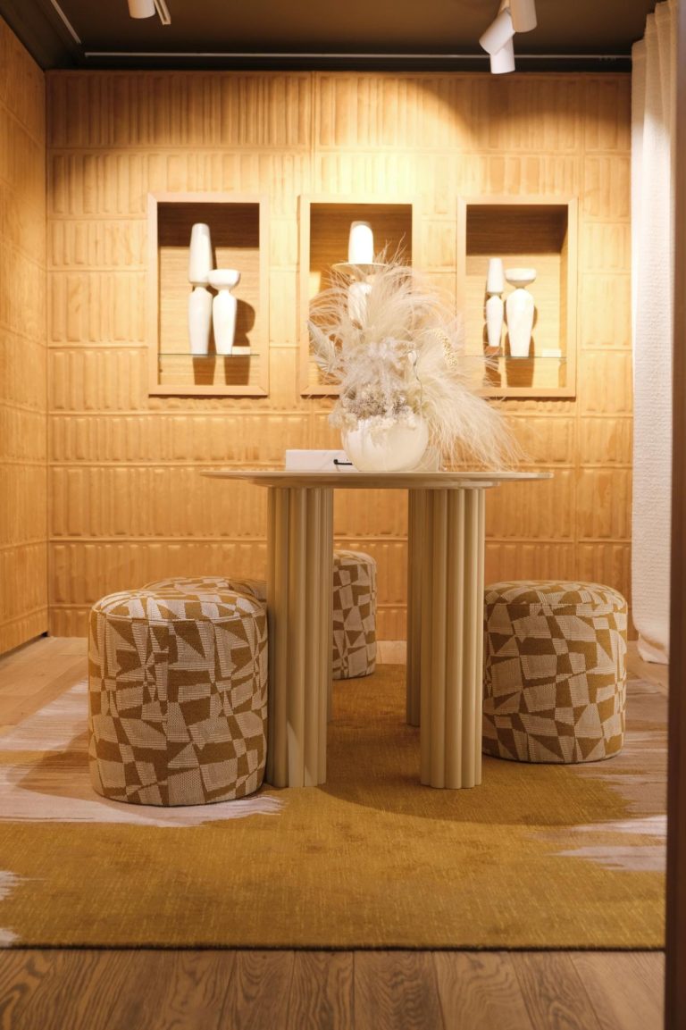 Decoración en tonos beige, mesa de madera con ramo de flores secas. Pared de madera con nicho en el que se colocan jarrones blancos.