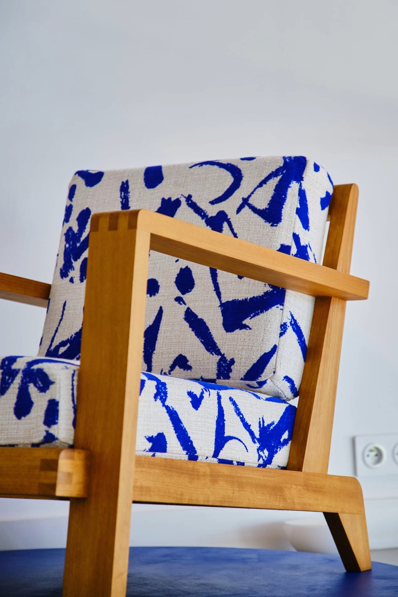 Silla de madera con asiento y respaldo tapizados con tela blanca y azul.
