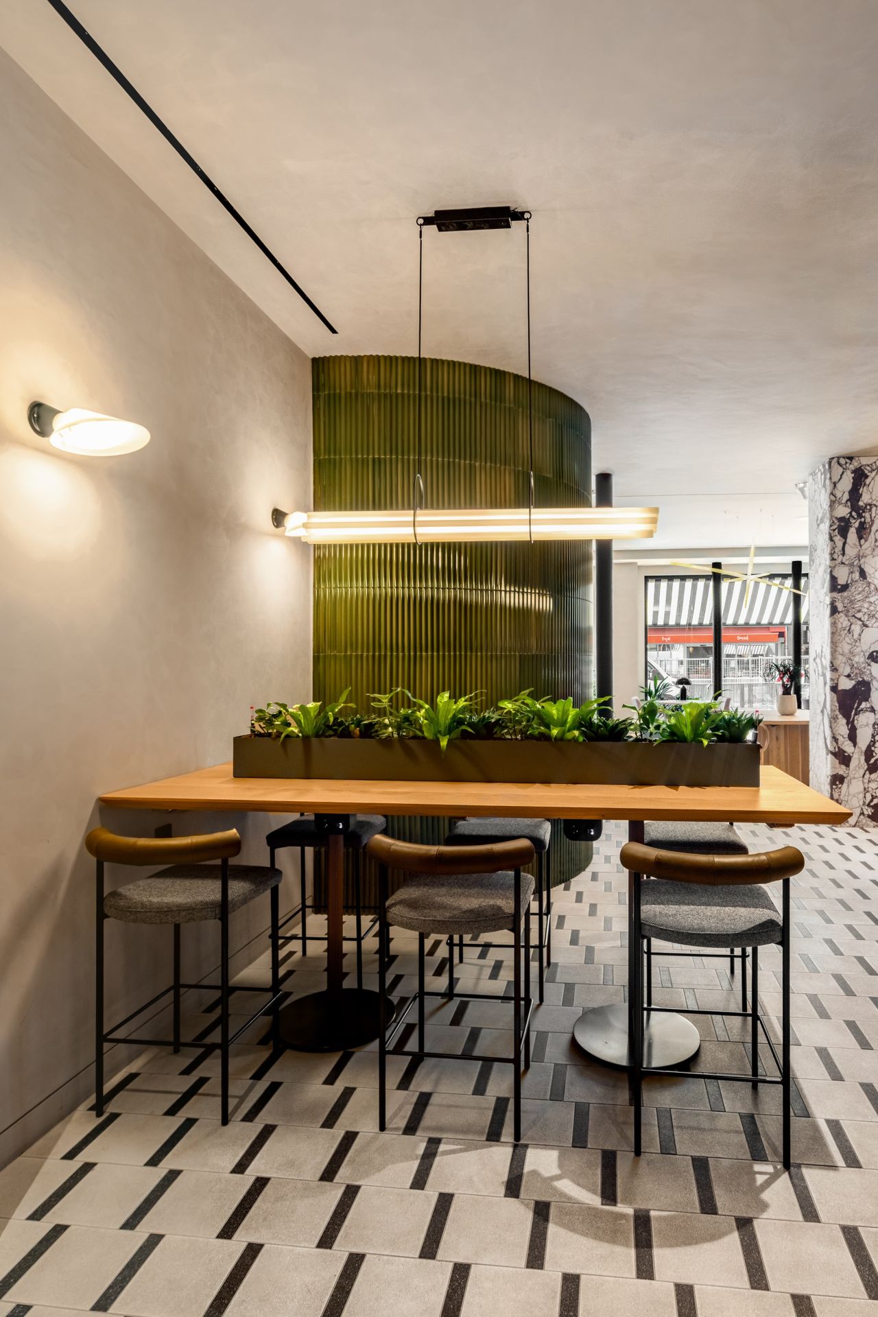 mesa de madera clara, silla de metal negro, pared con azulejos verdes