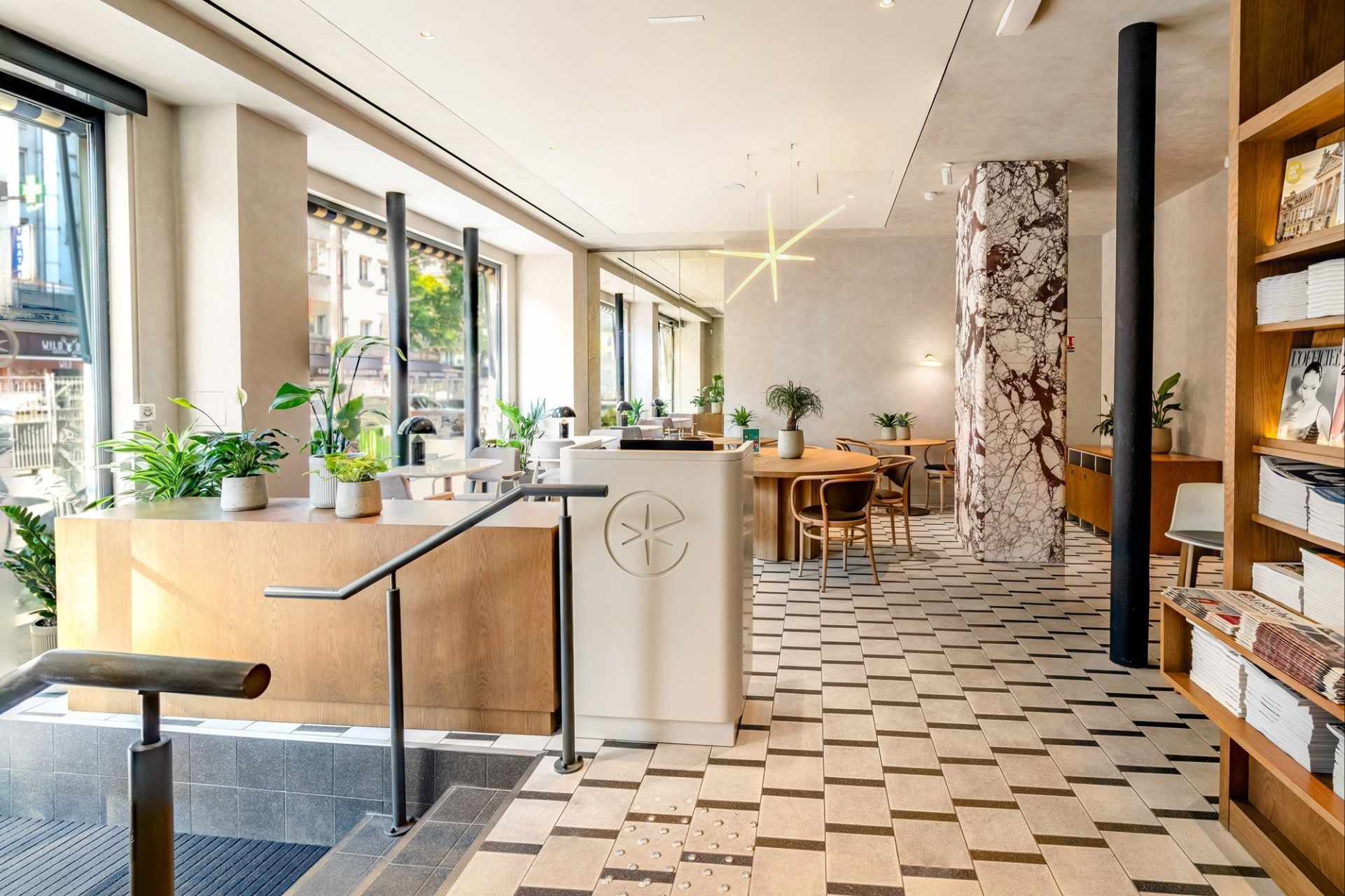 Interior del salón, baldosas blancas y negras, vigas de mármol, paredes blancas, muebles de madera clara.