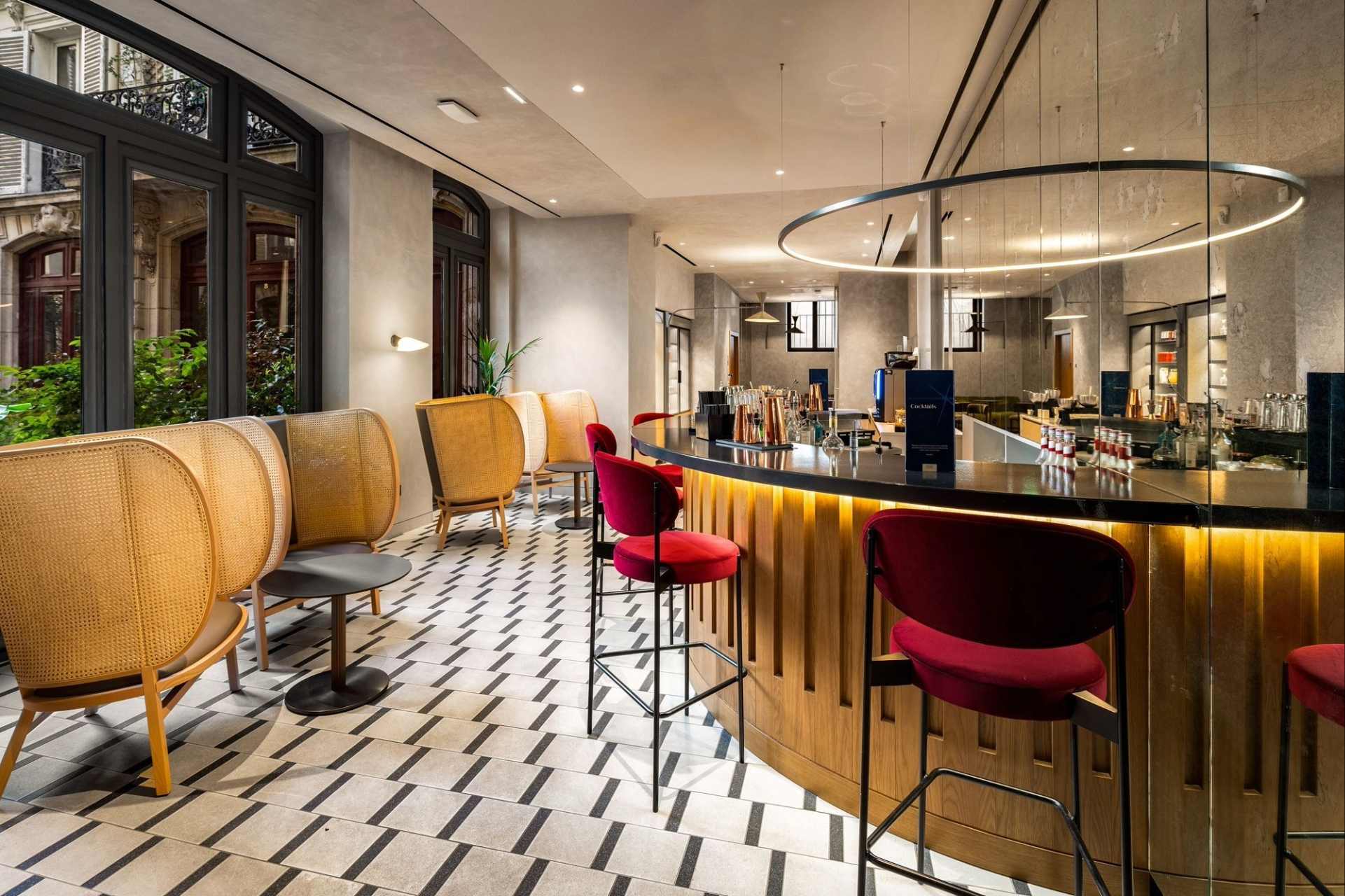 Vista desde el bar de madera, con baldosas blancas y negras y sillas rojas y negras.