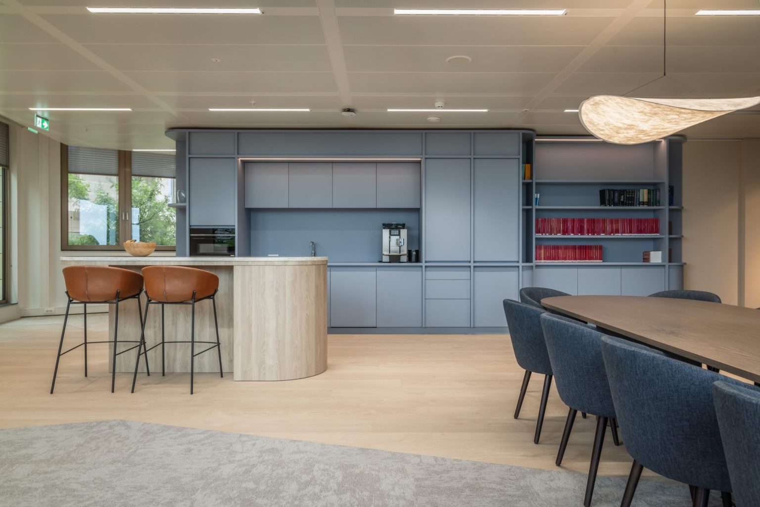 Visto en la zona de cocina, mesa alta y mesa grande, colores: beige, azul, madera clara.