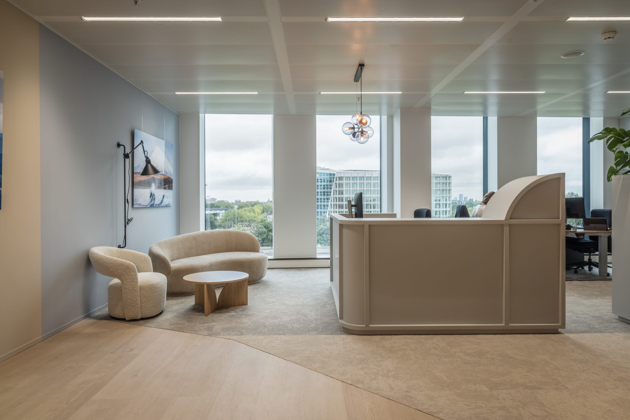 Sala de espera, sofá y sillón beige, ventana grande, moqueta gris.