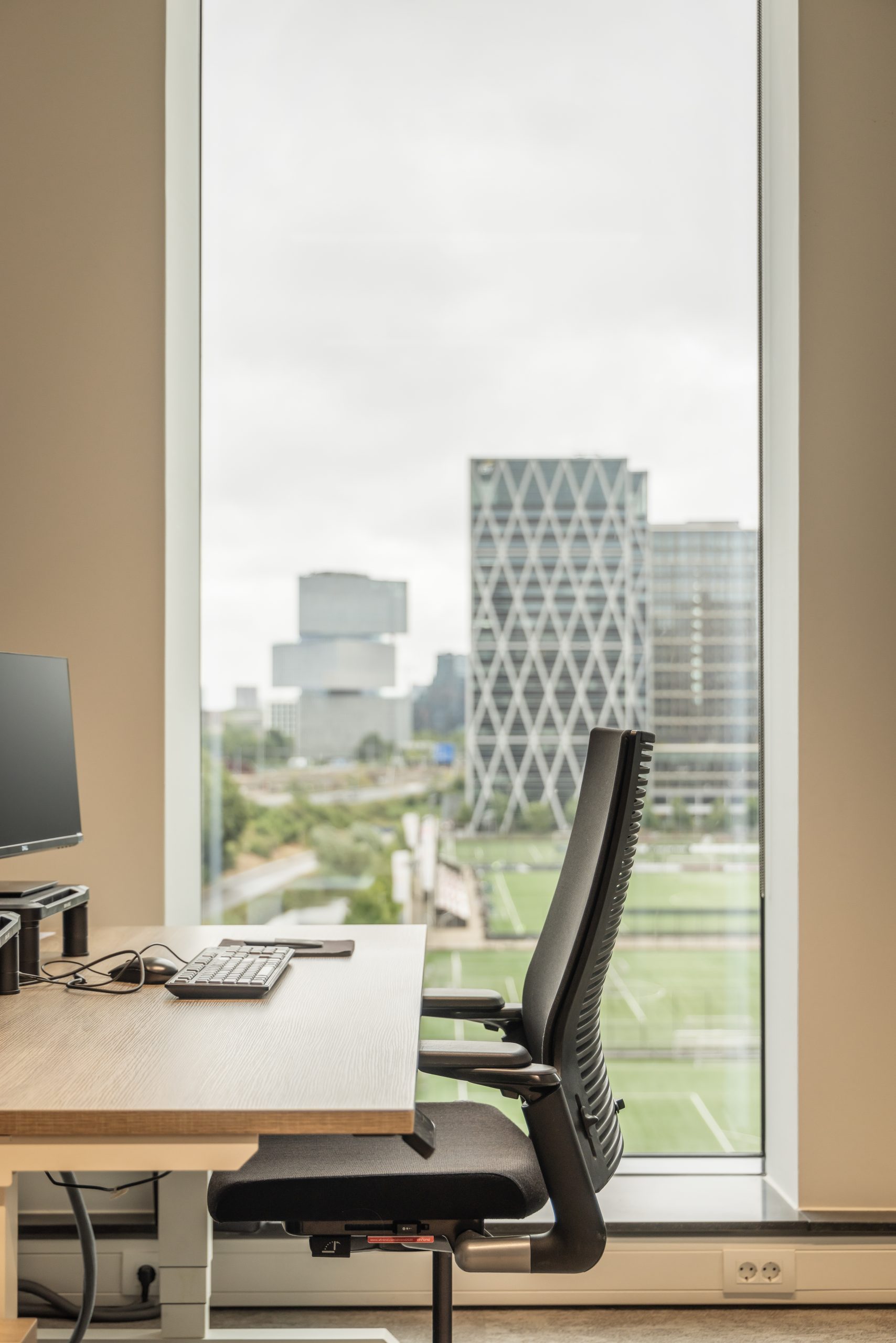 Silla de oficina negra, delante de una ventana.
