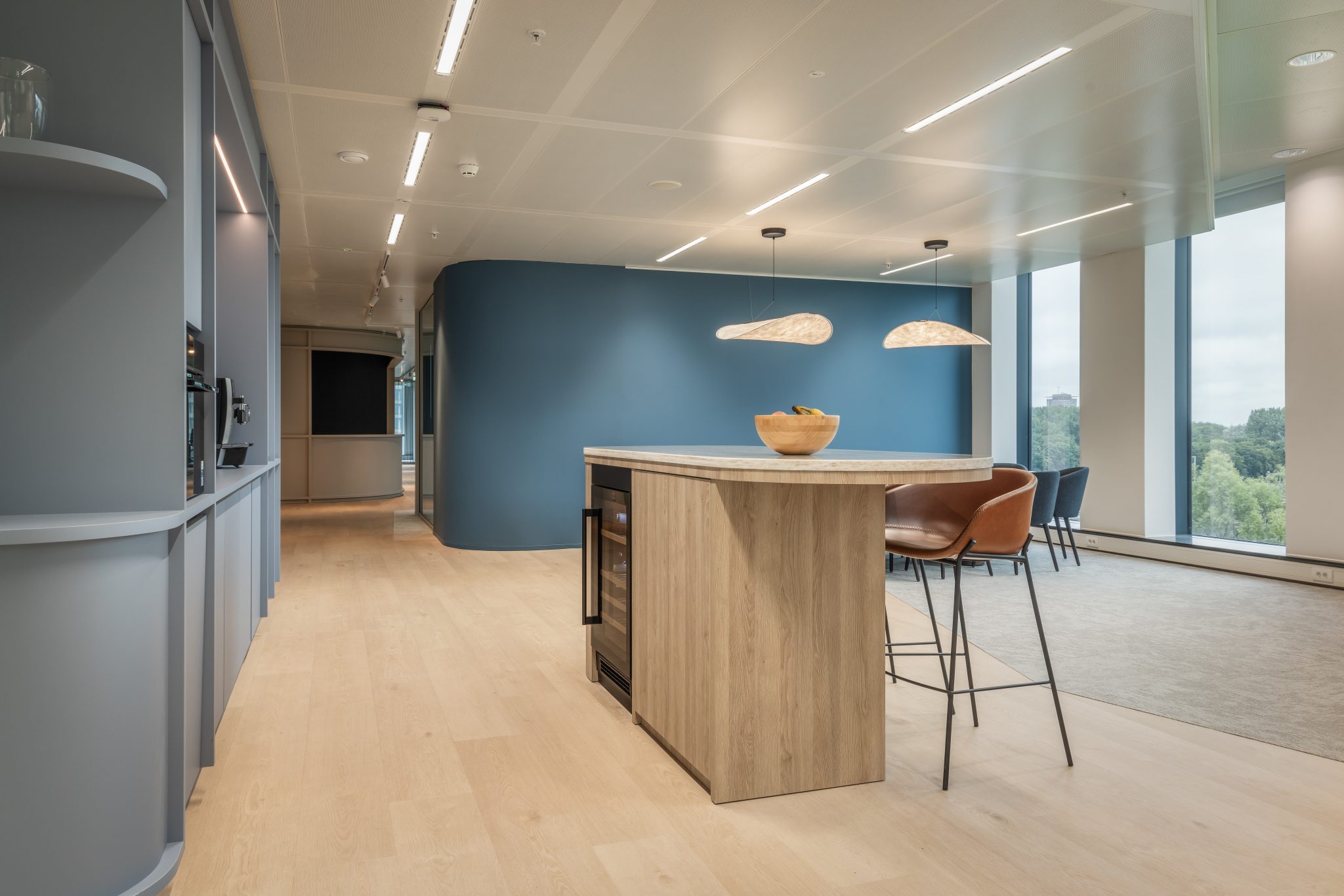 Visto sobre una mesa alta de madera gris claro, en la zona de cafetería. Pared azul.